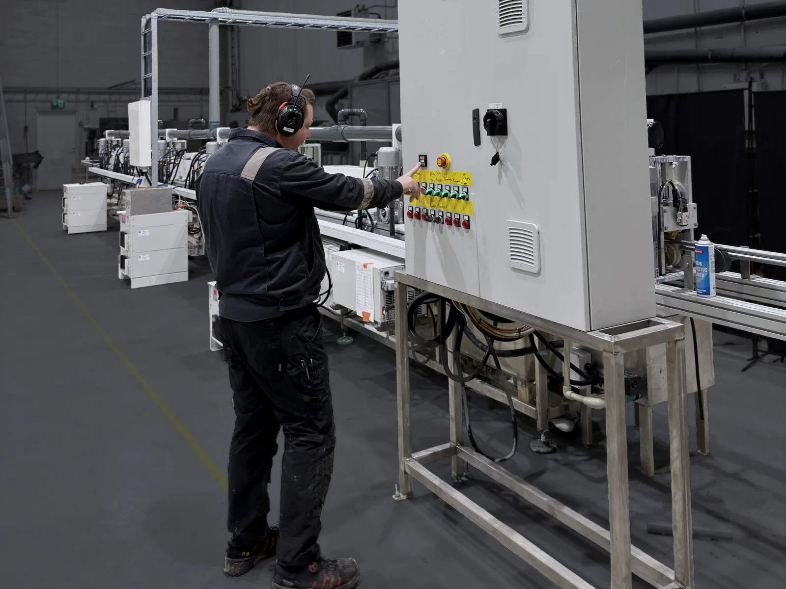 An operator works the control cabinet of the TripleHard® line in Kuopio, the coating cells running in the background