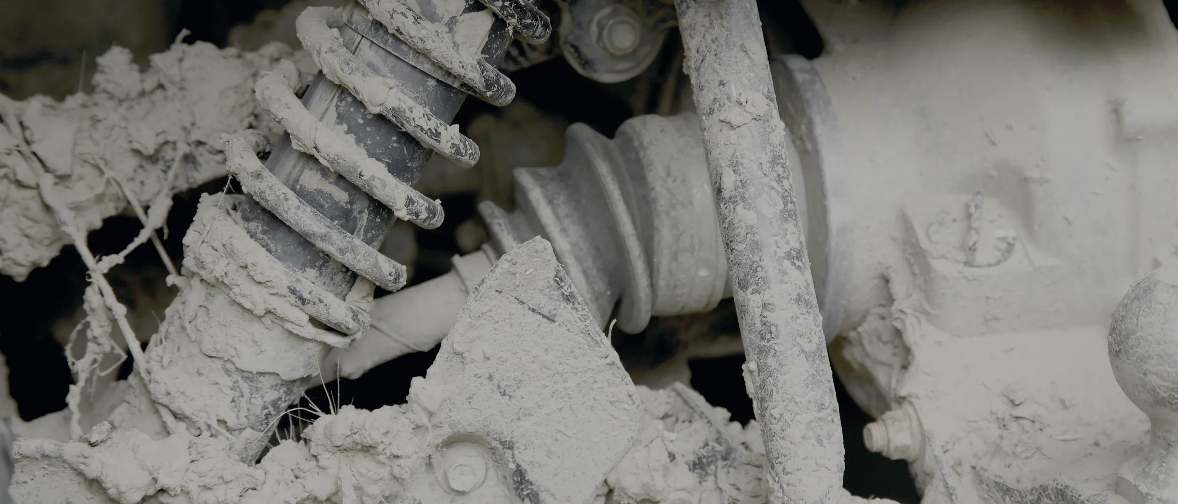 A shock absorber and coil spring caked in dried mud on a working vehicle