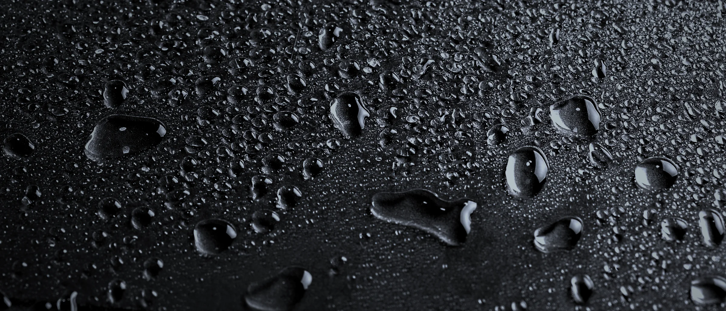 Water beading on a dark metal surface