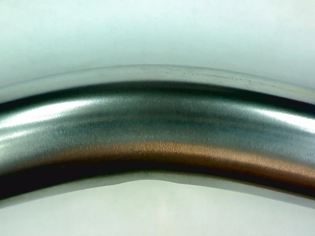 A bent TripleHard® coated steel rod, photographed from the side: the coating on the outside of the bend is smooth and continuous, with no peeling or flaking