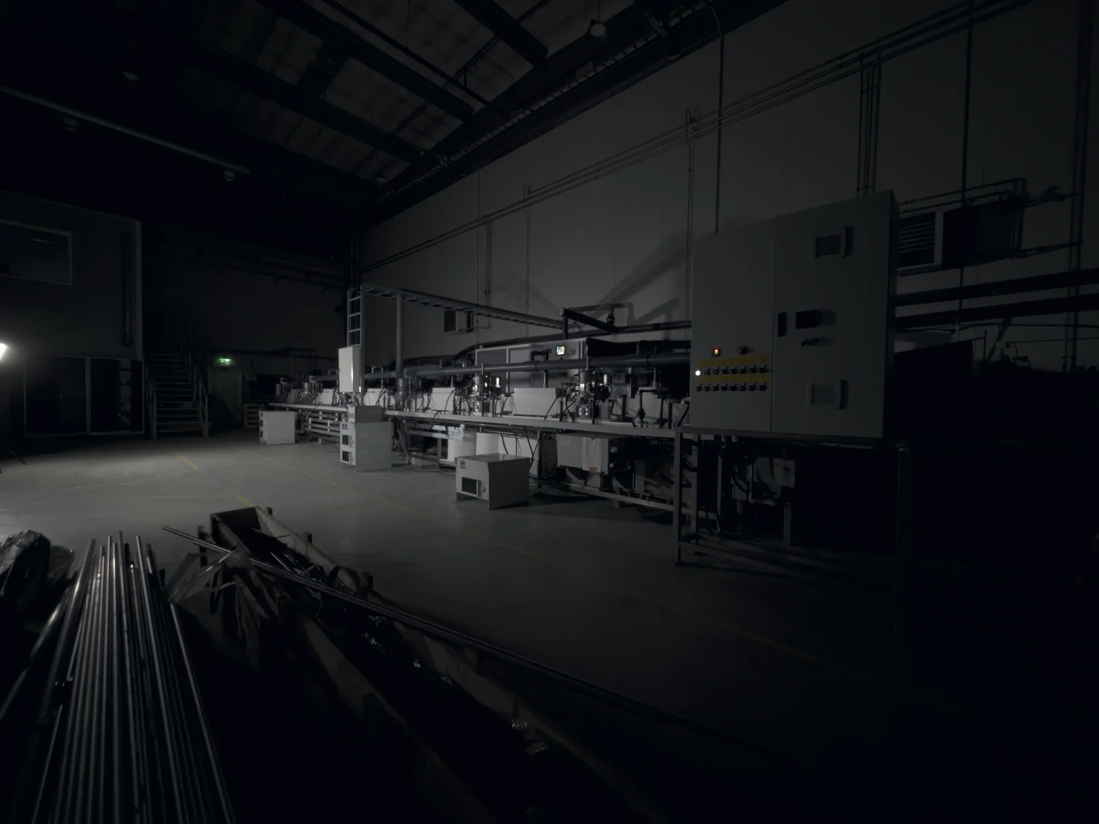 The continuous TripleHard® line in Kuopio seen from the side in the darkened hall, with a bundle of rods waiting in the foreground